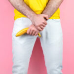 potency and men's health a man in white jeans legs apart holds a banana