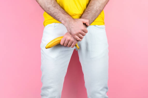 potency and men's health a man in white jeans legs apart holds a banana