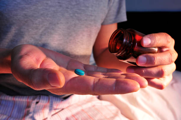 man in bed about to take a blue pill